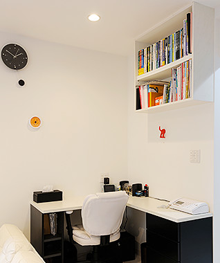 ご主人の書斎となる黒と白のL型デスクの上部には、空間を利用して吊り書棚を設置。